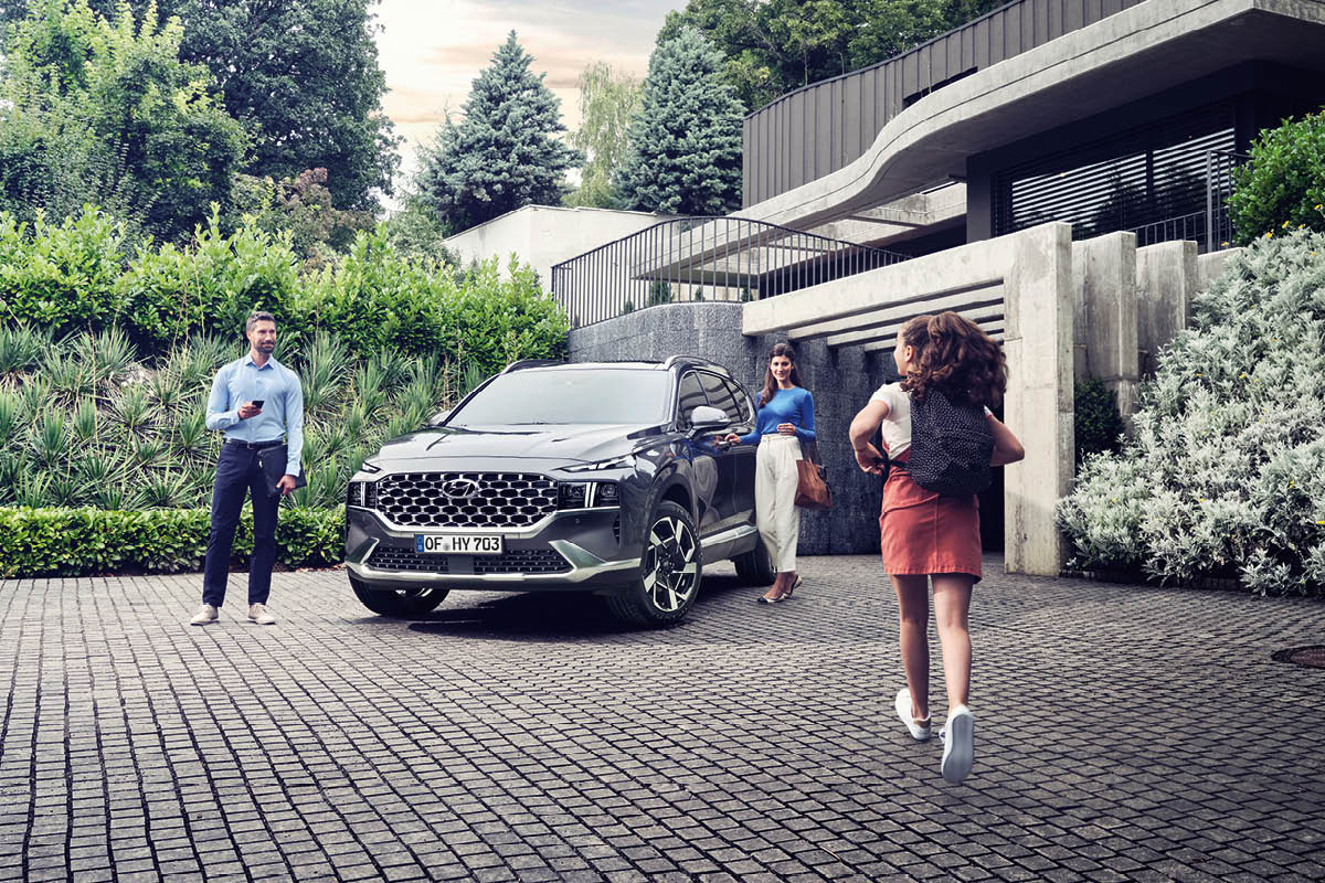 zu sehen ist ein Hyundai SANTA FE vor einer Garage mit Familie