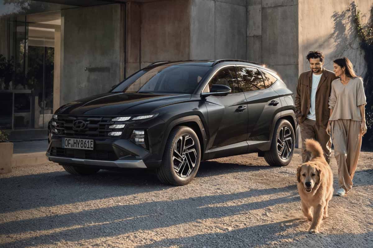 zu sehen ist ein Hyundai Tucson, daneben geht ein Paar und ein Hund