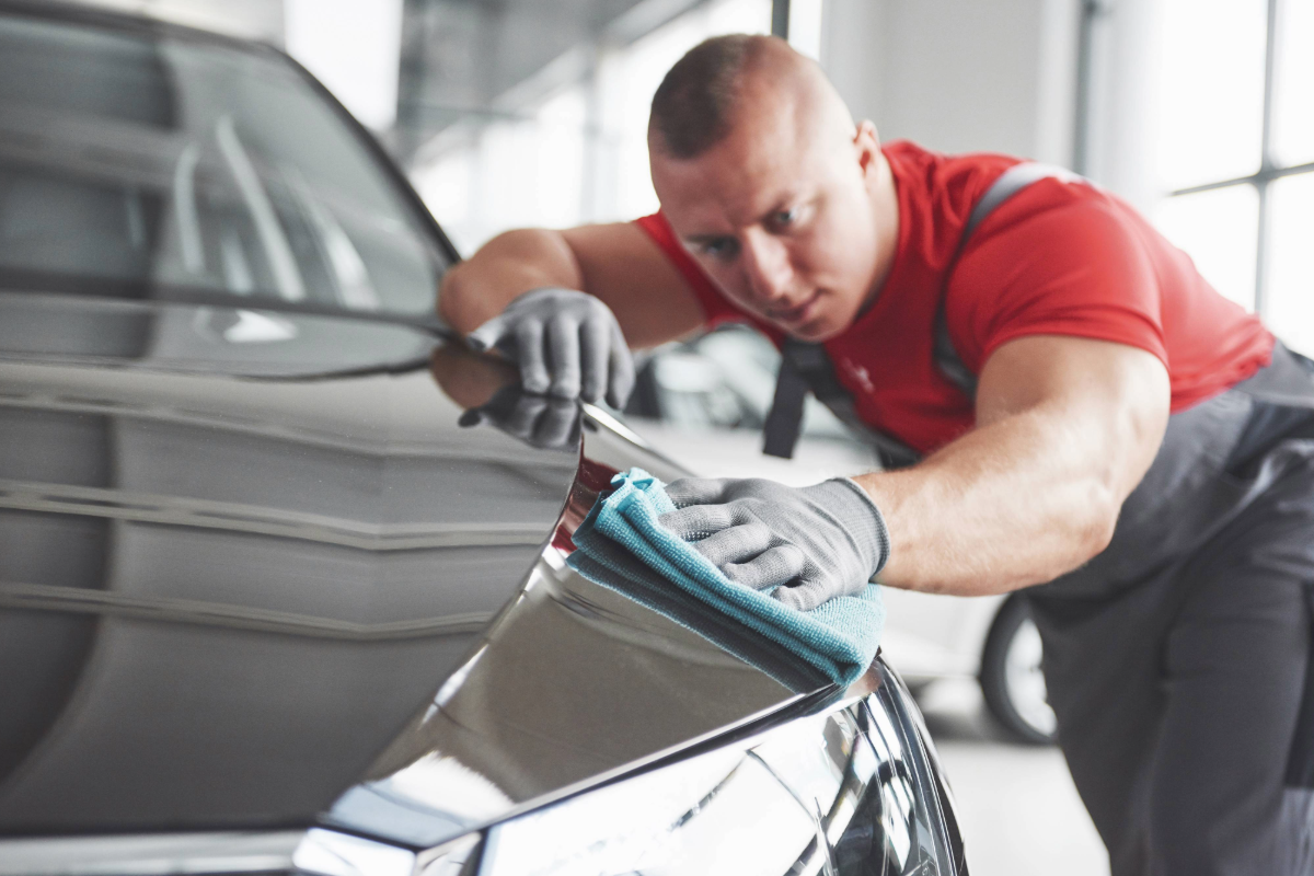 zu sehen ist ein KFZ Mitarbeiter, der ein Auto poliert